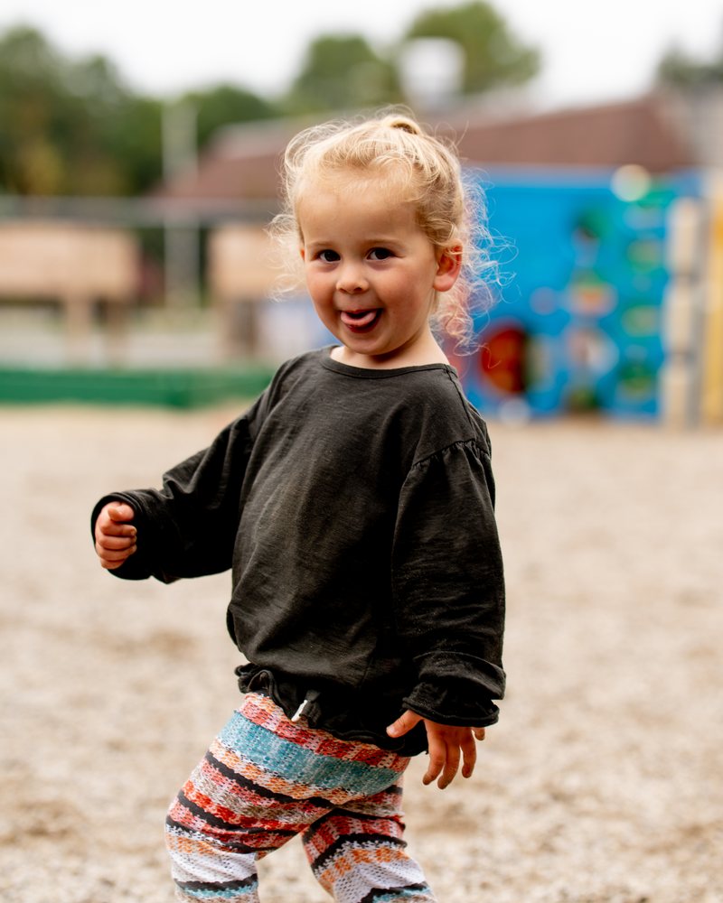 A toddler sticking out her tongue on the playground