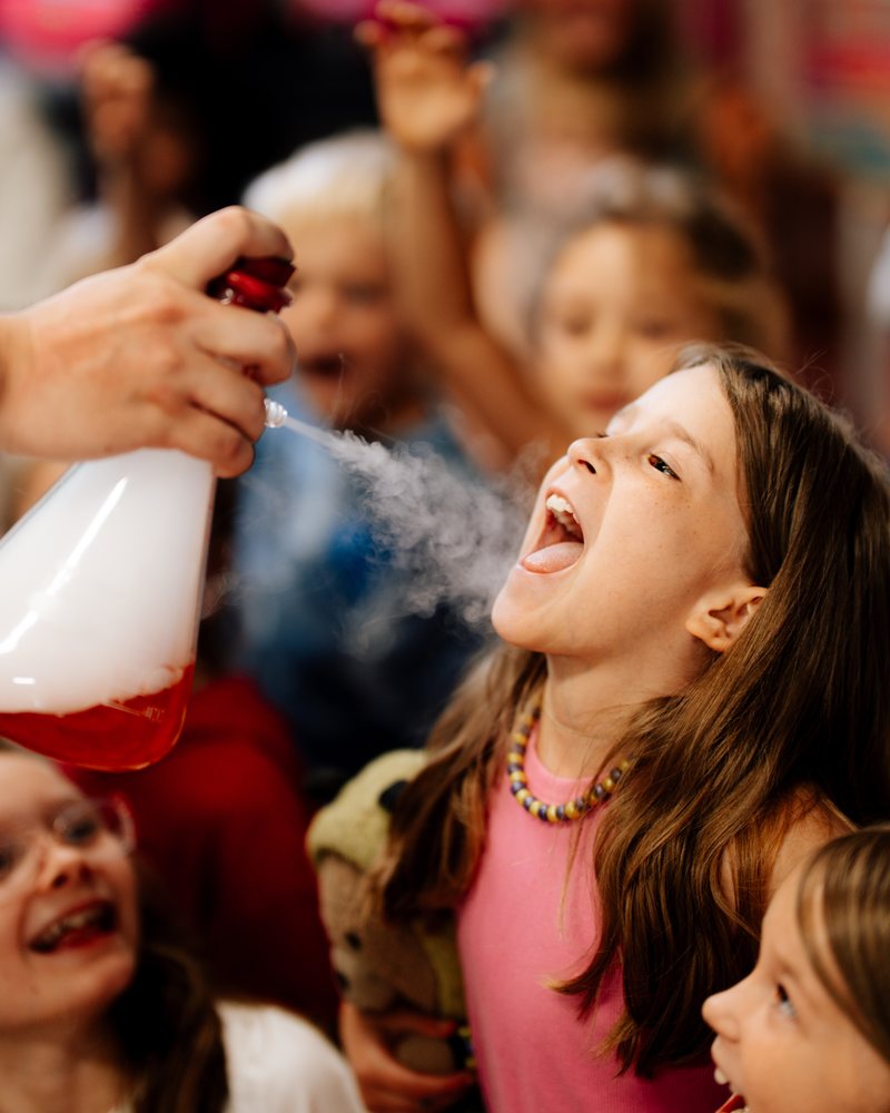 A girl catching a cloud of vapor on her tongue at the science show
