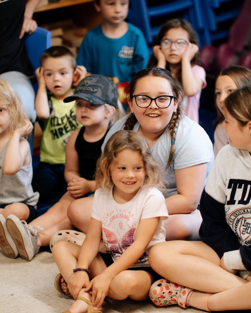 Children and a teacher sitting together at the science show