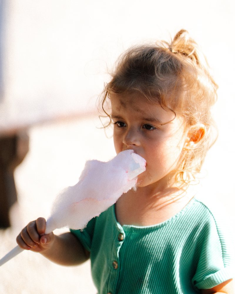 A girl eating cotton candy at the carnival