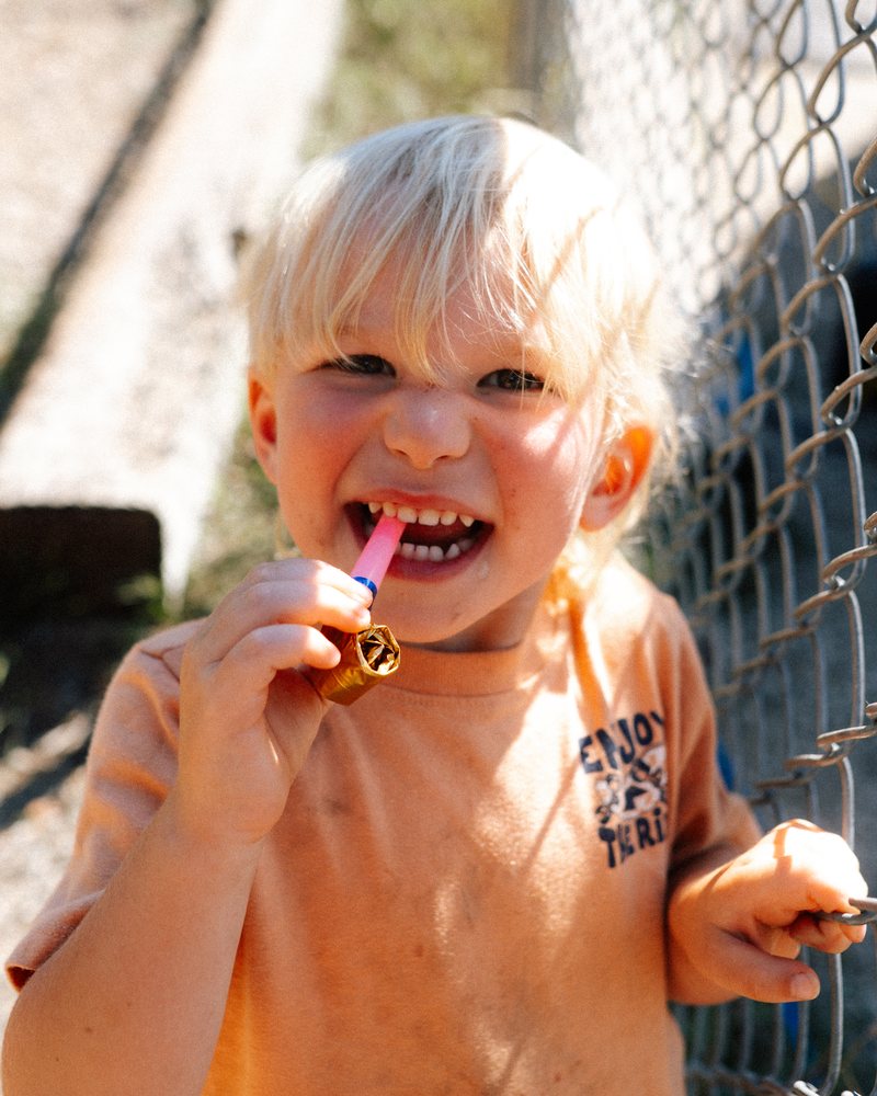 A boy with a party blower in his teeth at the carnival