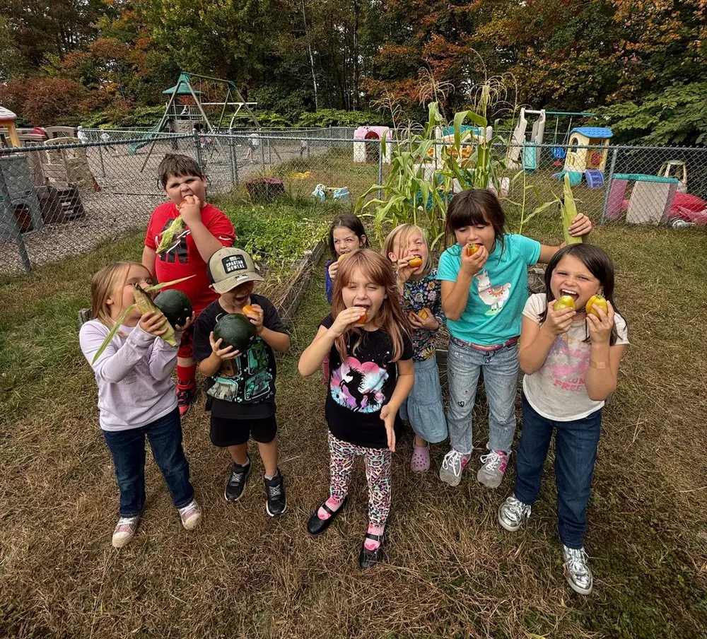 Kids & Co. children eating vegetables they picked from the center garden