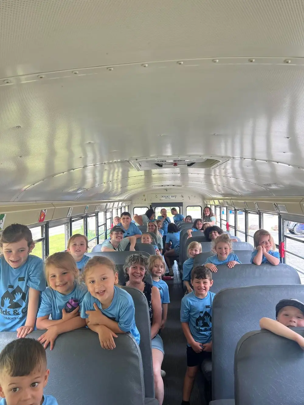 Summer campers in blue Kids & Co. shirts on the bus for a field trip